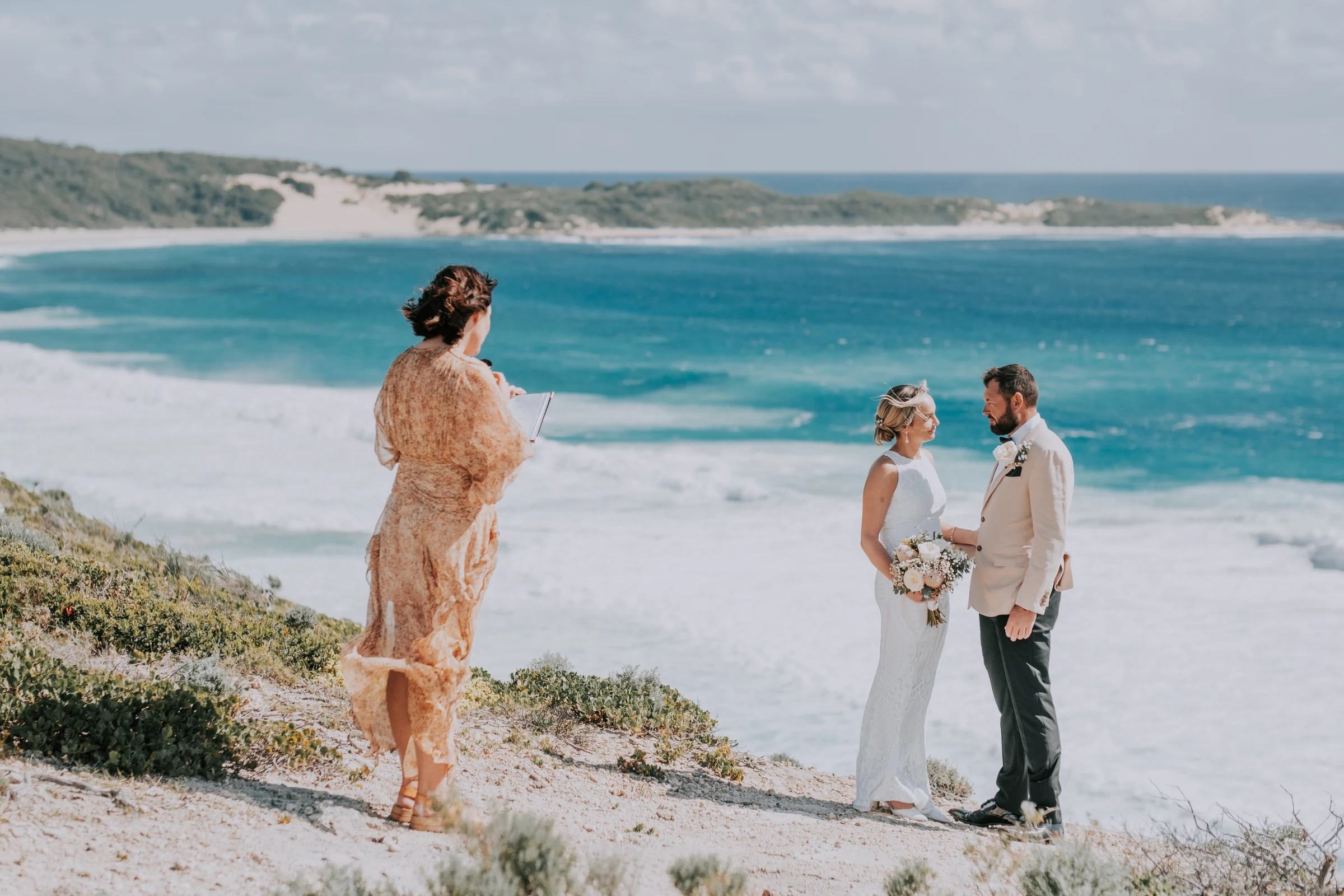 The celebrant reading the ceremony on the clifftop as Victoria and Luck face the turquoise bay at Injidup Beach