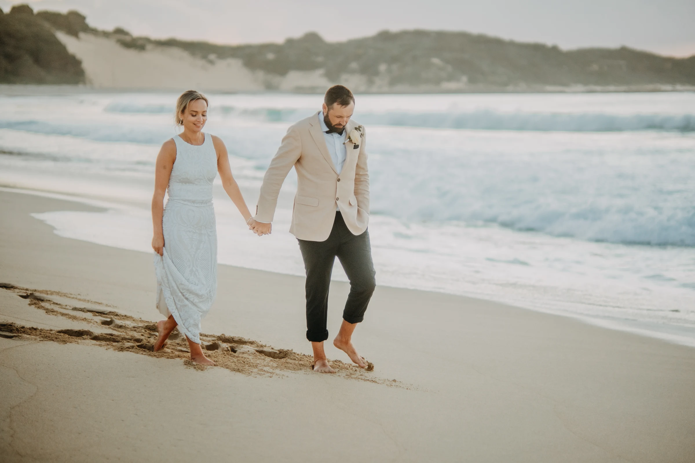 Victoria and Luck walking barefoot along the sand at Injidup Beach at dusk