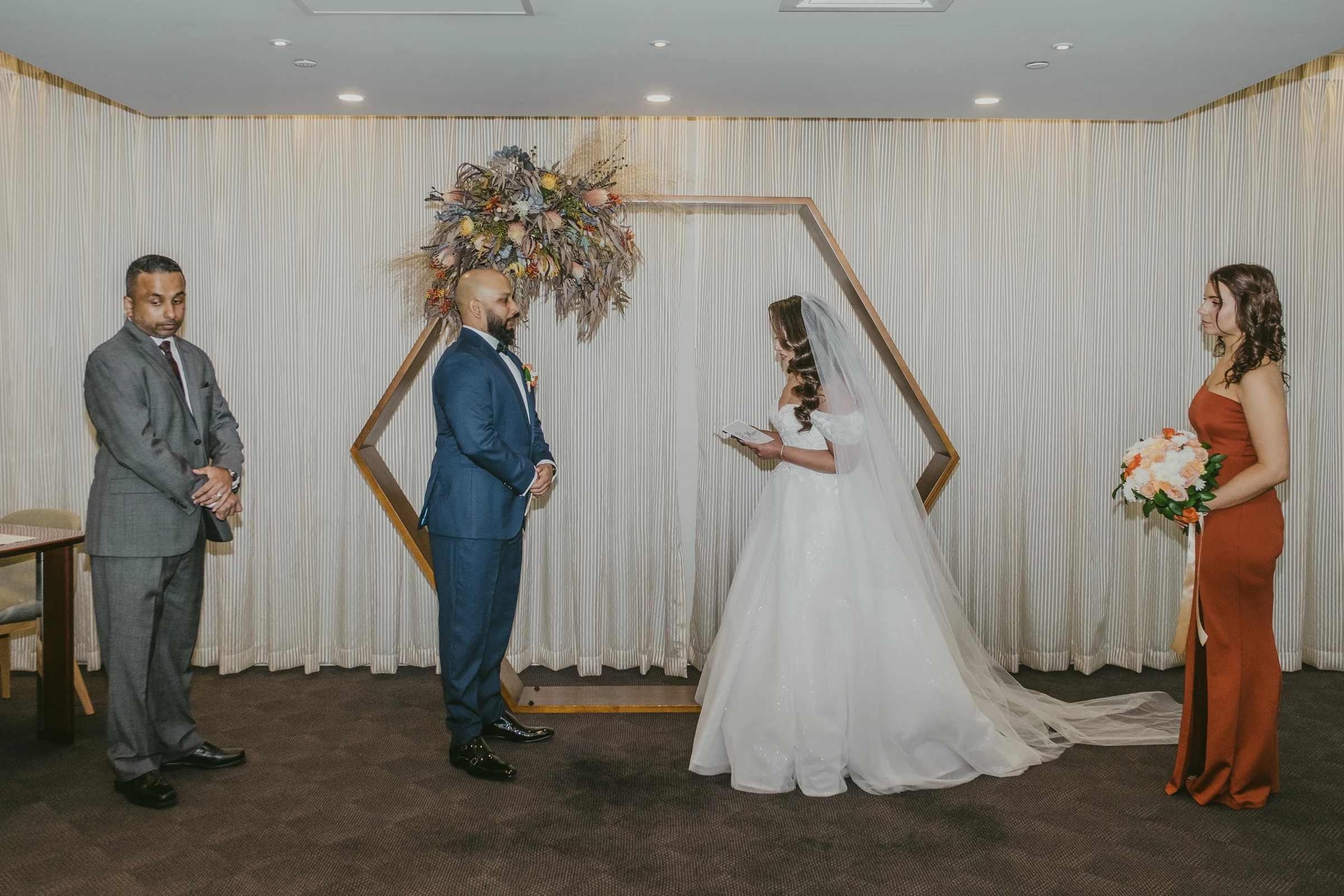 Betsy and Jibin exchanging vows in front of family and friends under a hexagon arch at the Registry of Births, Deaths & Marriages