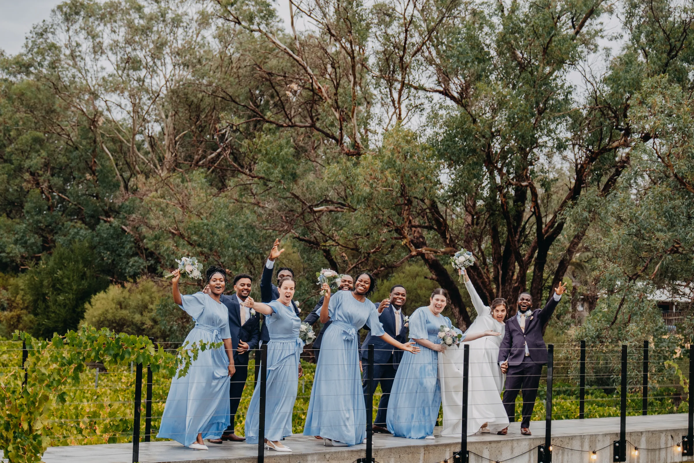 Cassandra and Jonathan's bridal party sheltering under umbrellas in the rain at Chapel Farm Estate