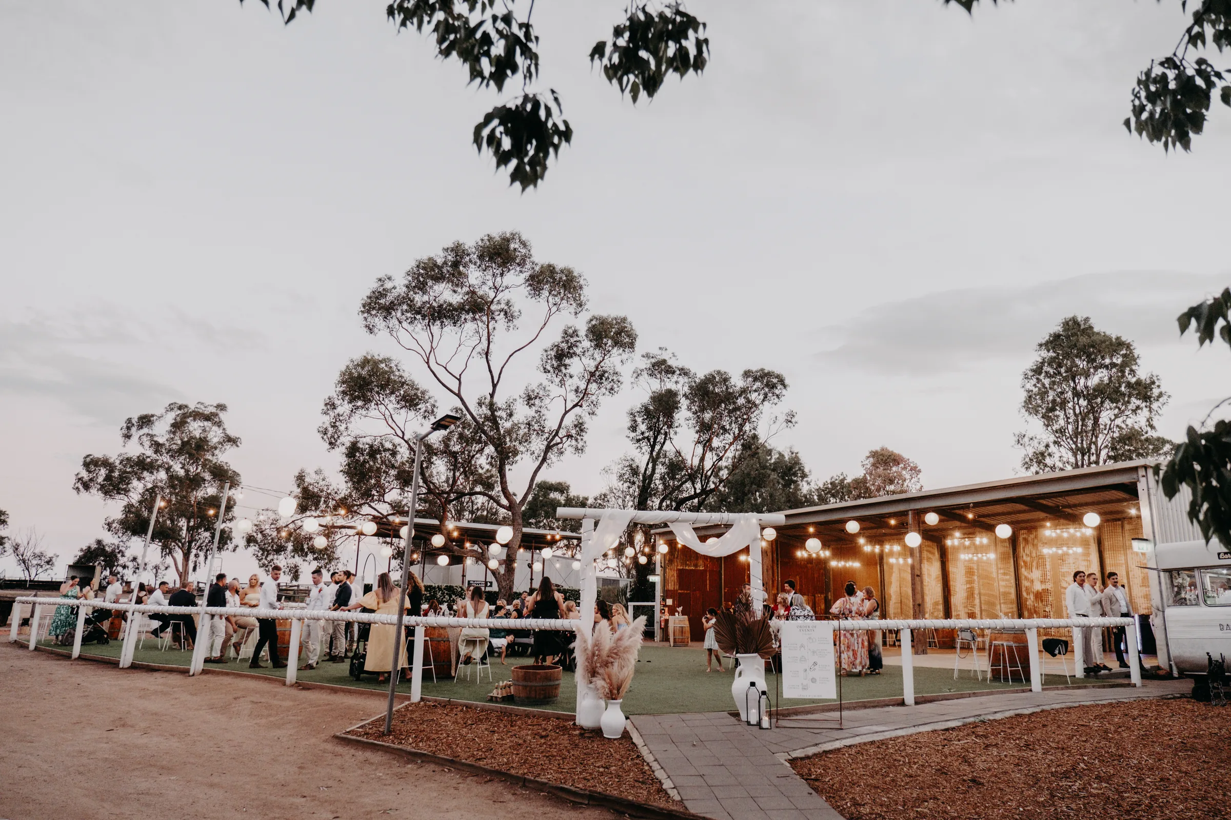 Buckland Estate's reception space strung with fairy lights at dusk as guests arrive