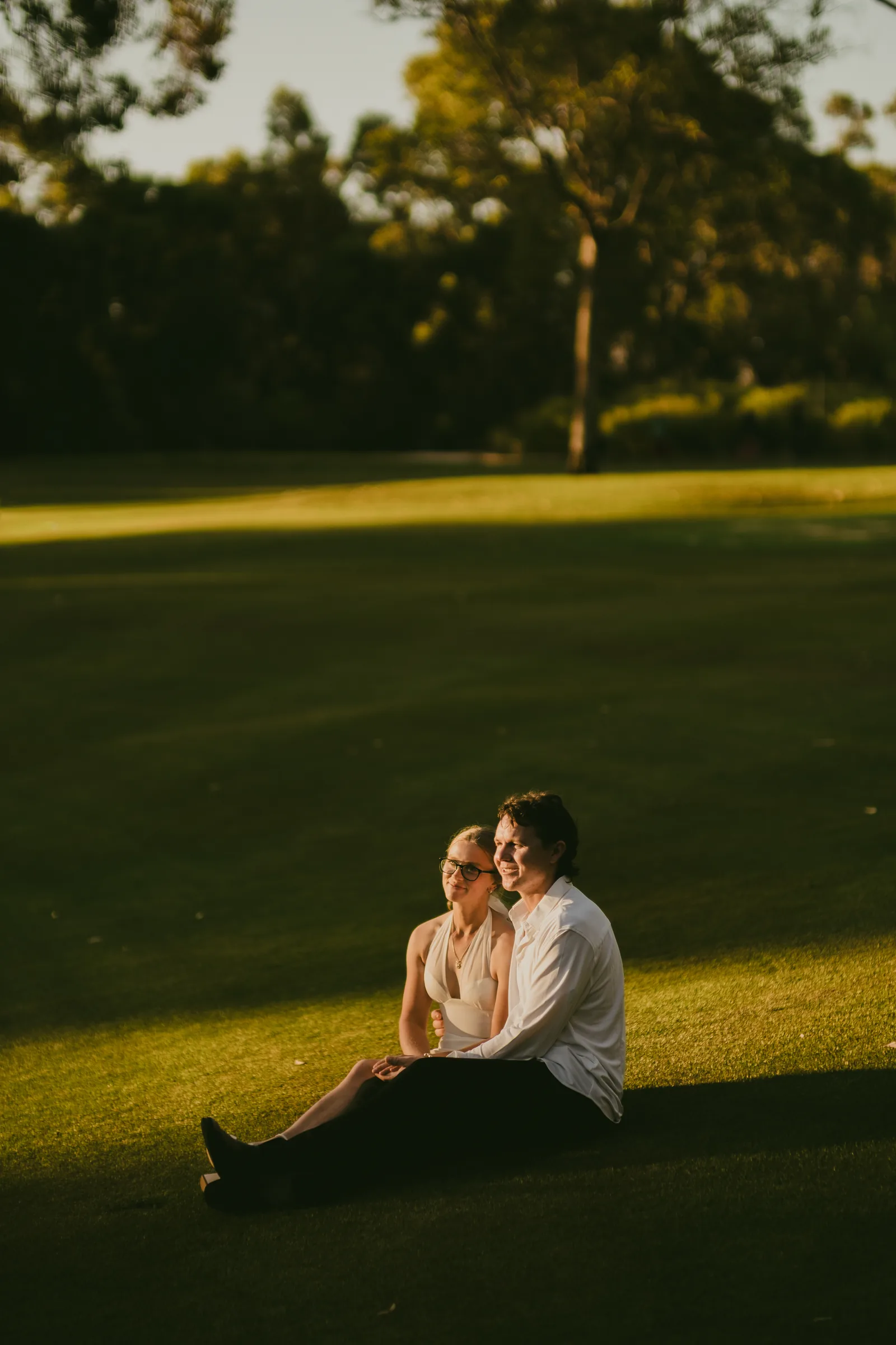 Kayla and Brett sitting together on the grass in Kings Park at sunset