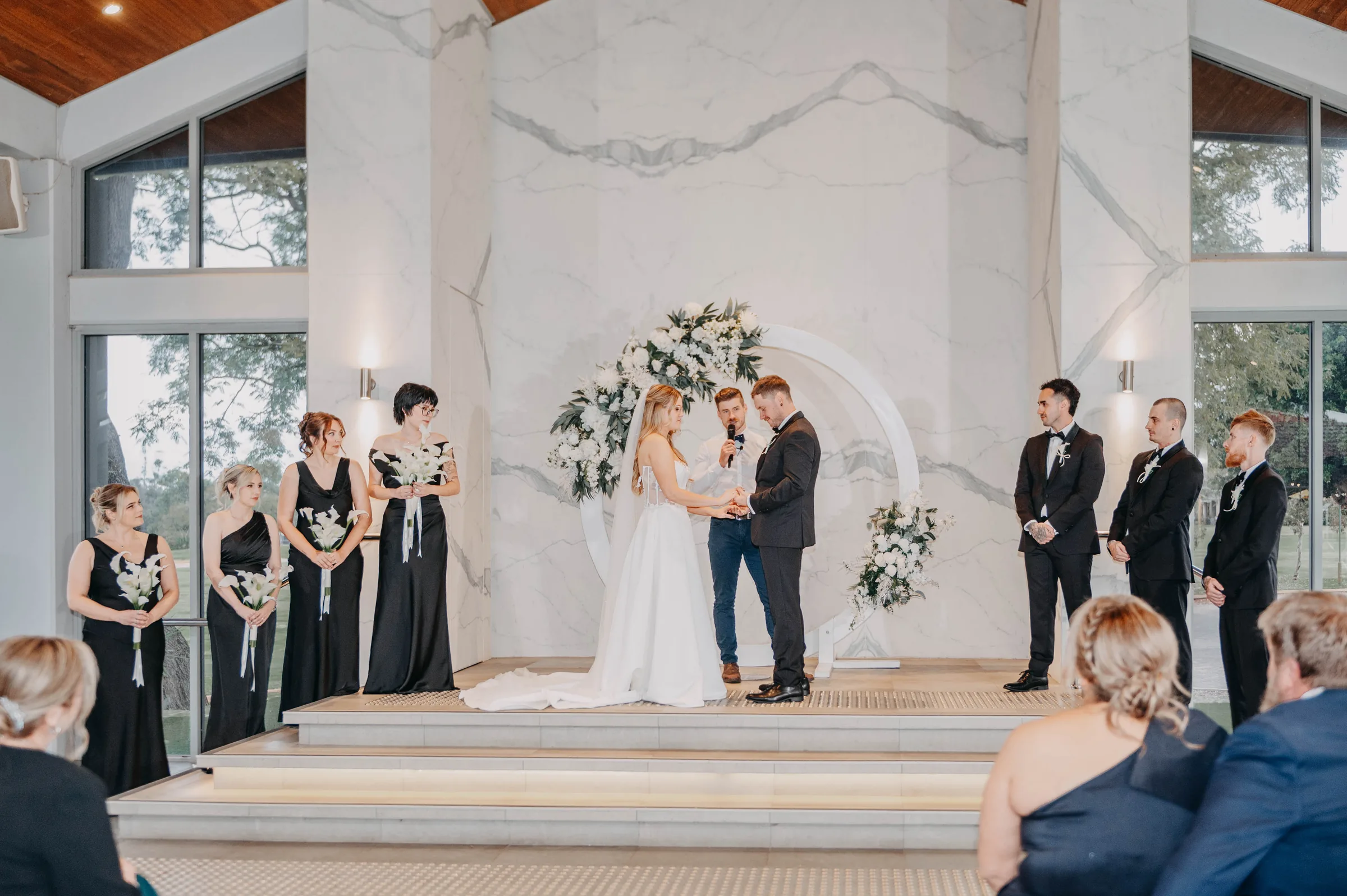 Kirra walking down the aisle at the Garden Pavilion as guests watch on