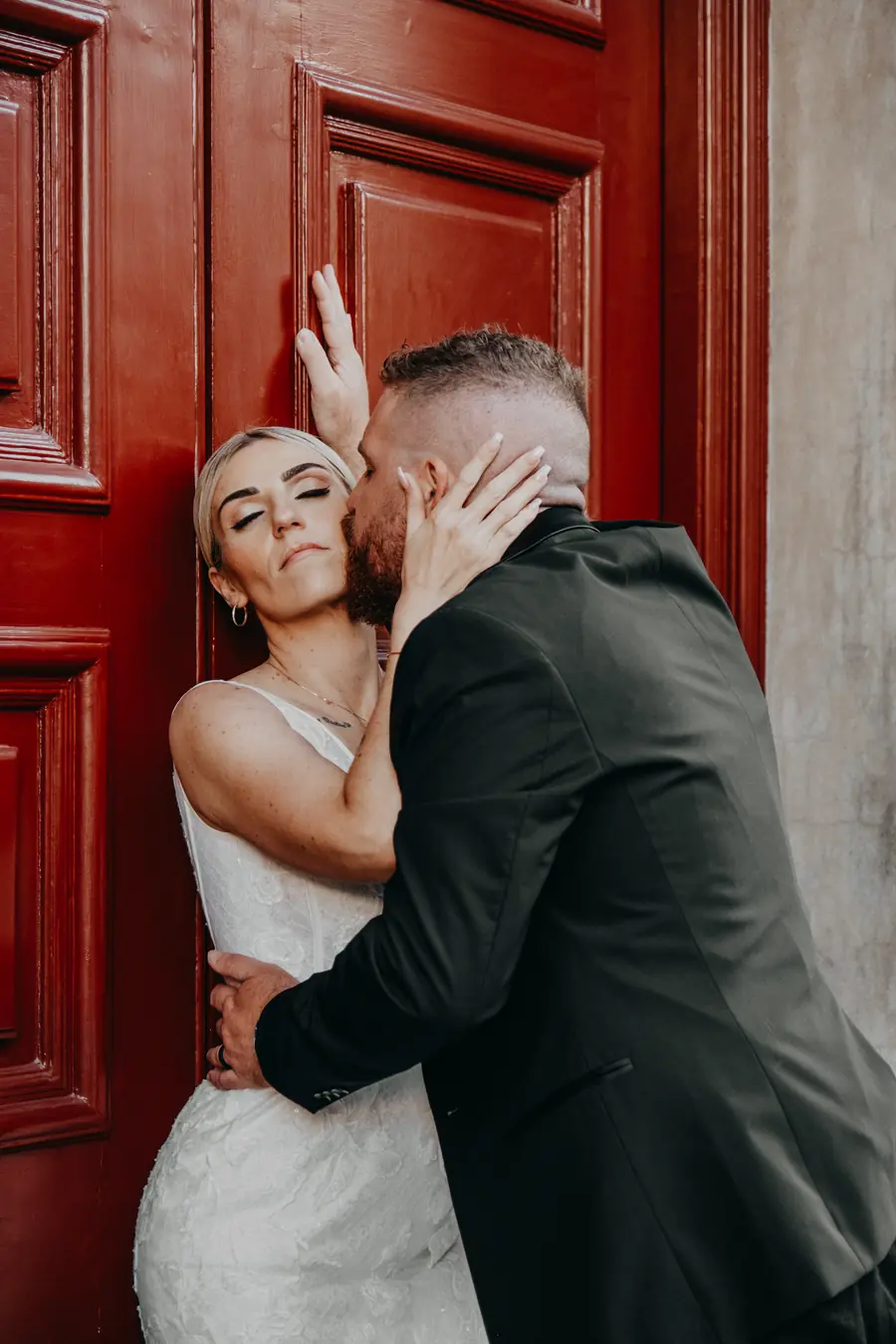 Bride and groom sharing an intimate moment against a red door near Supreme Court Gardens, Perth wedding photographer