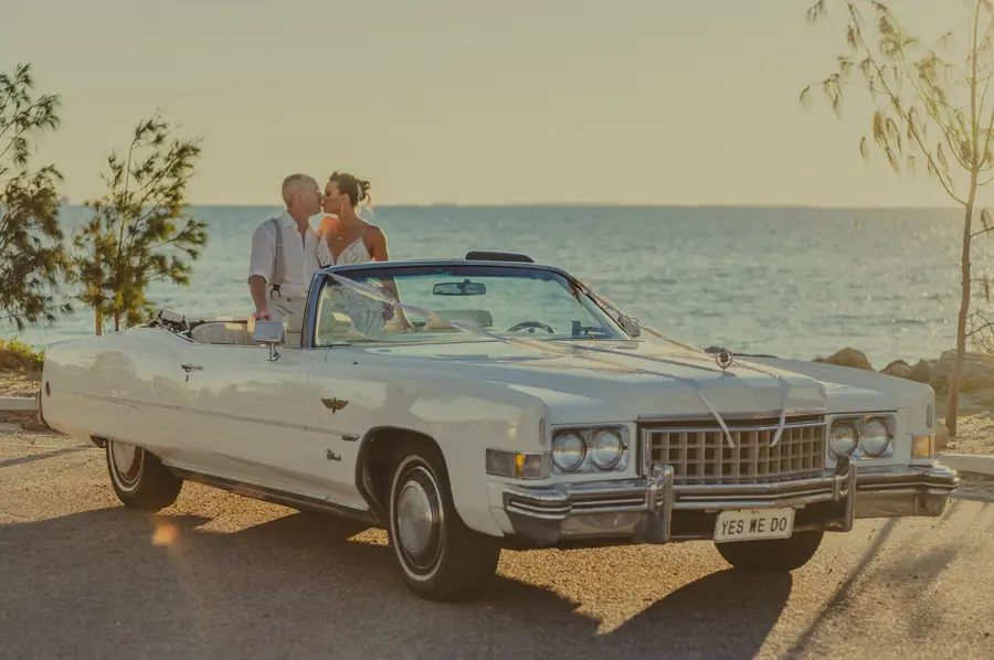Katia and Sean seated in a vintage convertible with bridal bouquet at Coast Port Beach, North Fremantle