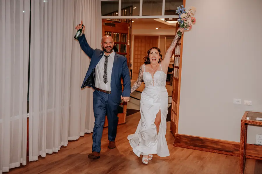 Bride and groom celebrating their reception entrance with a Heineken in hand at The Vines Resort