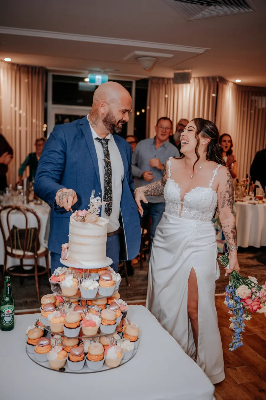 Kerry and Richard cutting their wedding cake surrounded by guests