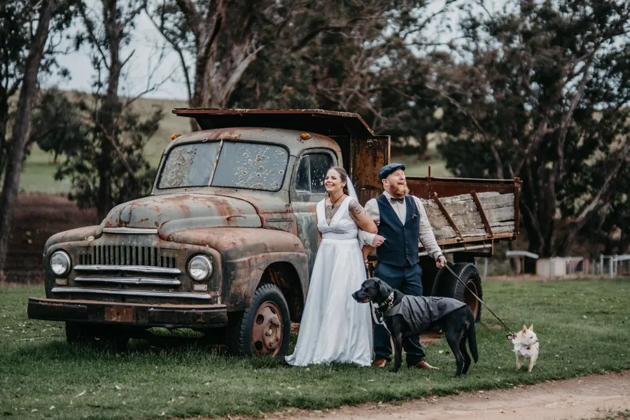 Bride and groom with their two dogs beside an old truck at their rustic Dalmore Farm wedding