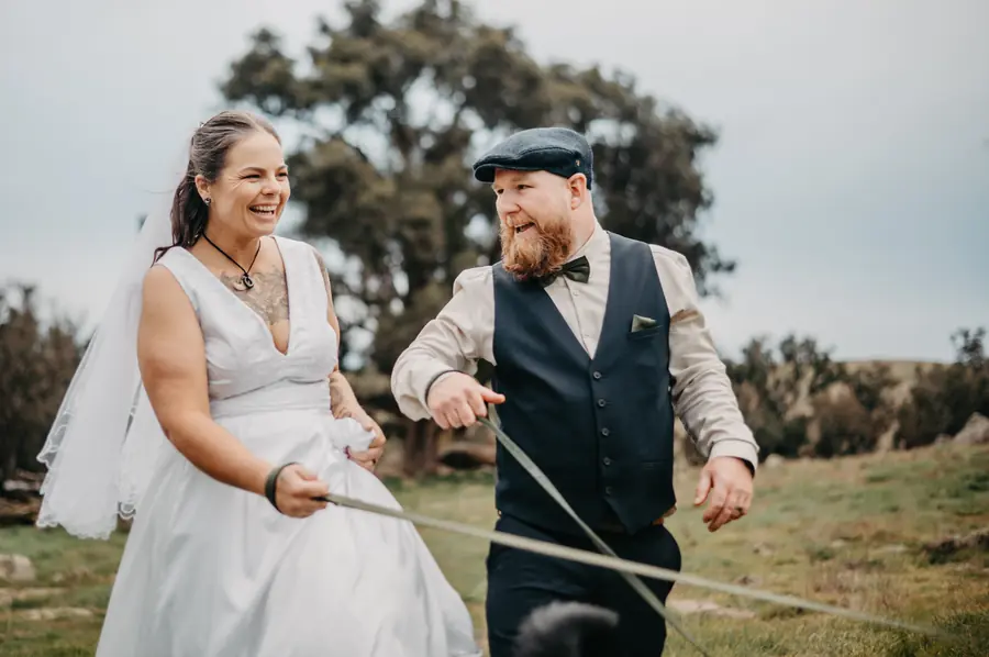 Groom in flat cap and waistcoat laughing with the bride during golden hour portraits at Dalmore Farm