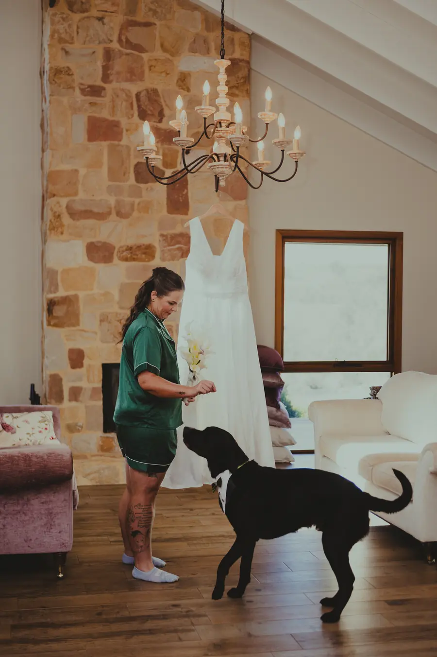Liv in green pyjamas with the family dog beside her wedding dress hanging in the farmhouse