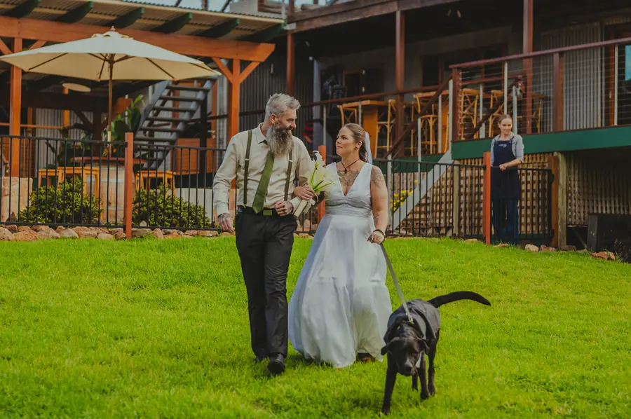 Ben and Liv walking their dog across the lawn towards the Dalmore Farm ceremony