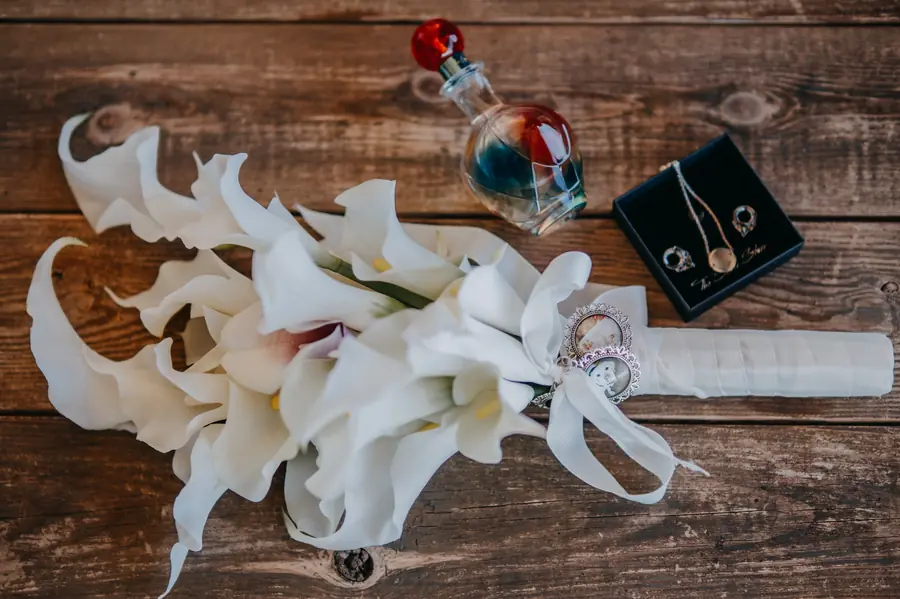 Bridal bouquet, perfume and jewellery flat lay on rustic timber at Dalmore Farm