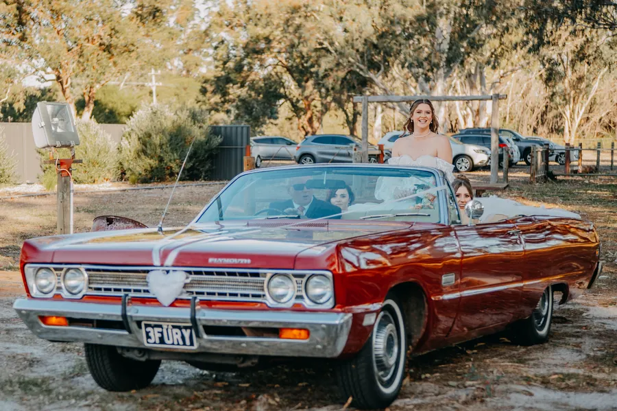 Bride arriving at The Barn, Hopeland in a vintage red Plymouth convertible with her bridesmaids