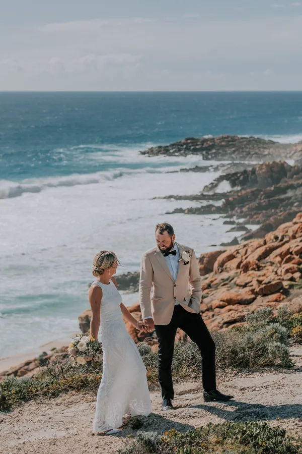 Victoria and Luck walking hand in hand along the clifftop path above the rocky Injidup coastline