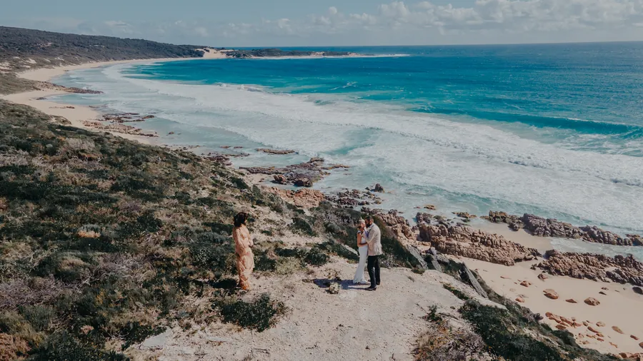 Aerial drone view of Victoria and Luck embracing on the cliff edge above Injidup Beach