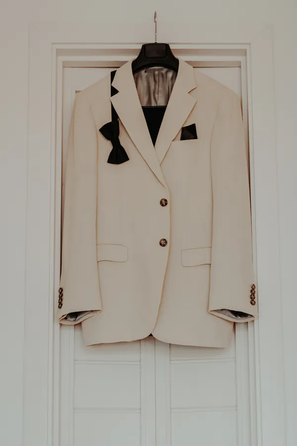 Luck's cream suit jacket and black bow tie hanging on the door before the ceremony