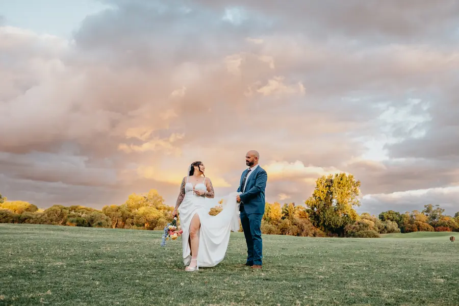 Kerry and Richard walking hand in hand across The Vines Resort golf course at golden hour with kangaroos in the background, Perth wedding photography