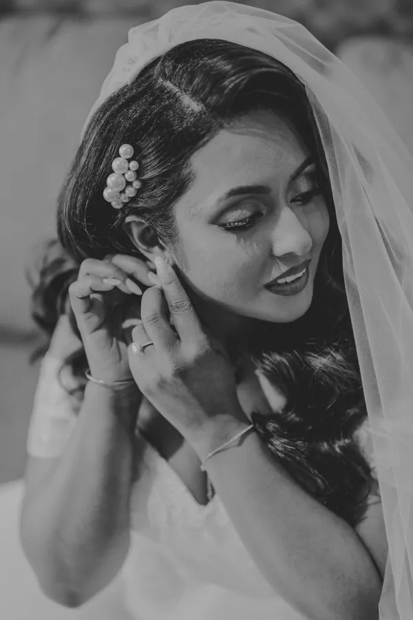 Black and white close-up of Betsy having her earring put in before the ceremony