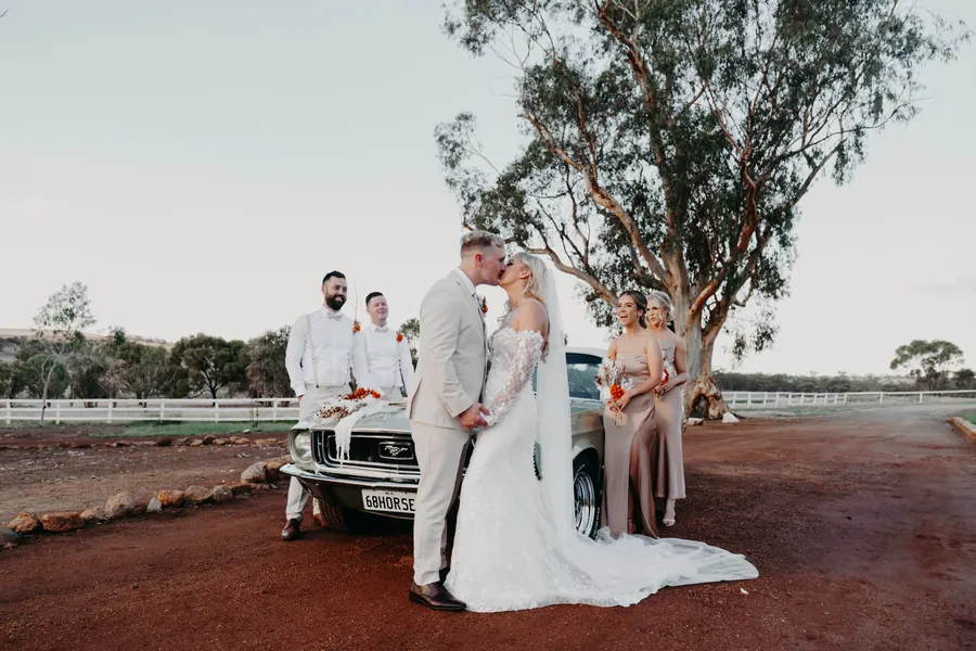 Grace and Lachie with their full wedding party posed beside the vintage car at Buckland Estate